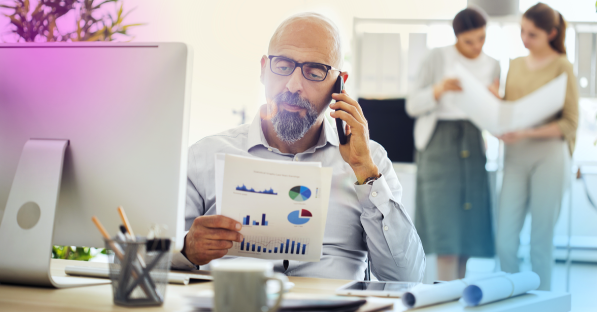 man looking at statistics with two women in the background speaking